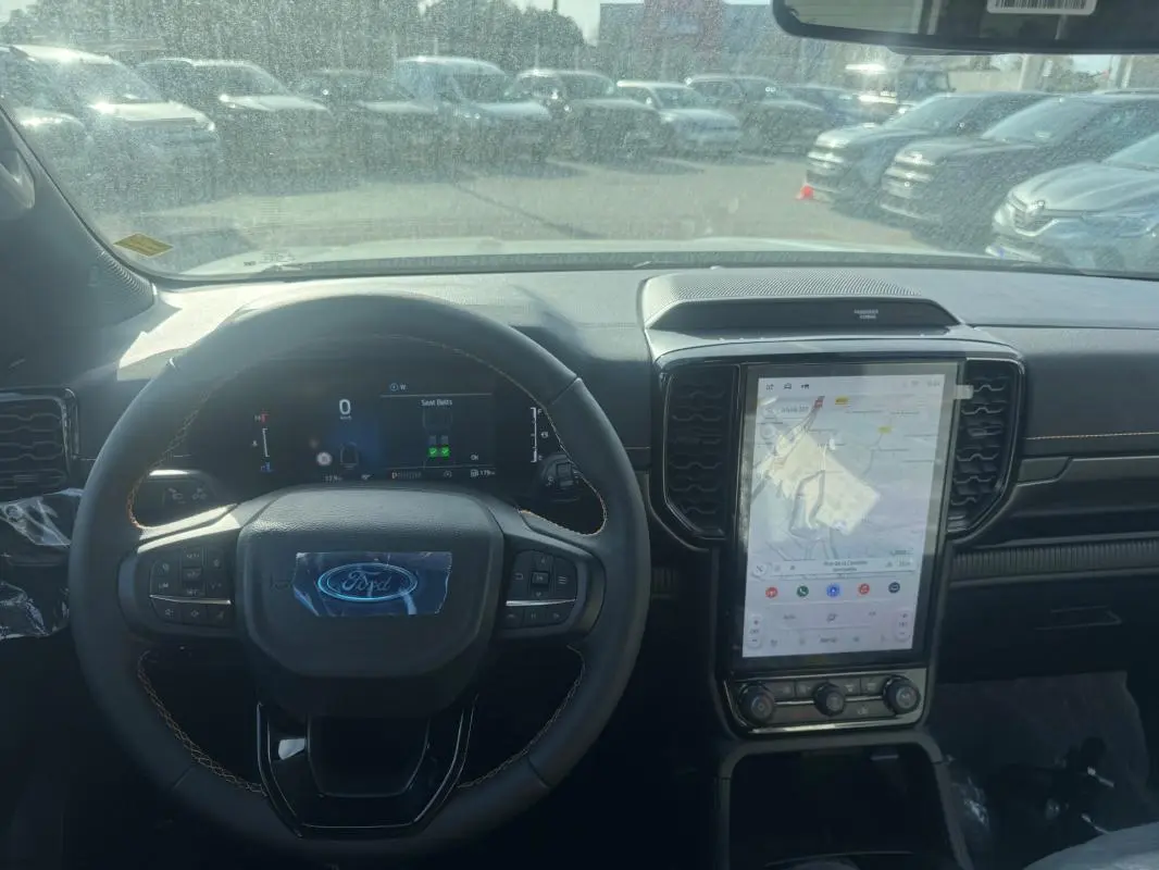 Vue intérieure centrée sur le volant multifonctions et l'écran tactile vertical du Ford Ranger gris 2025.
