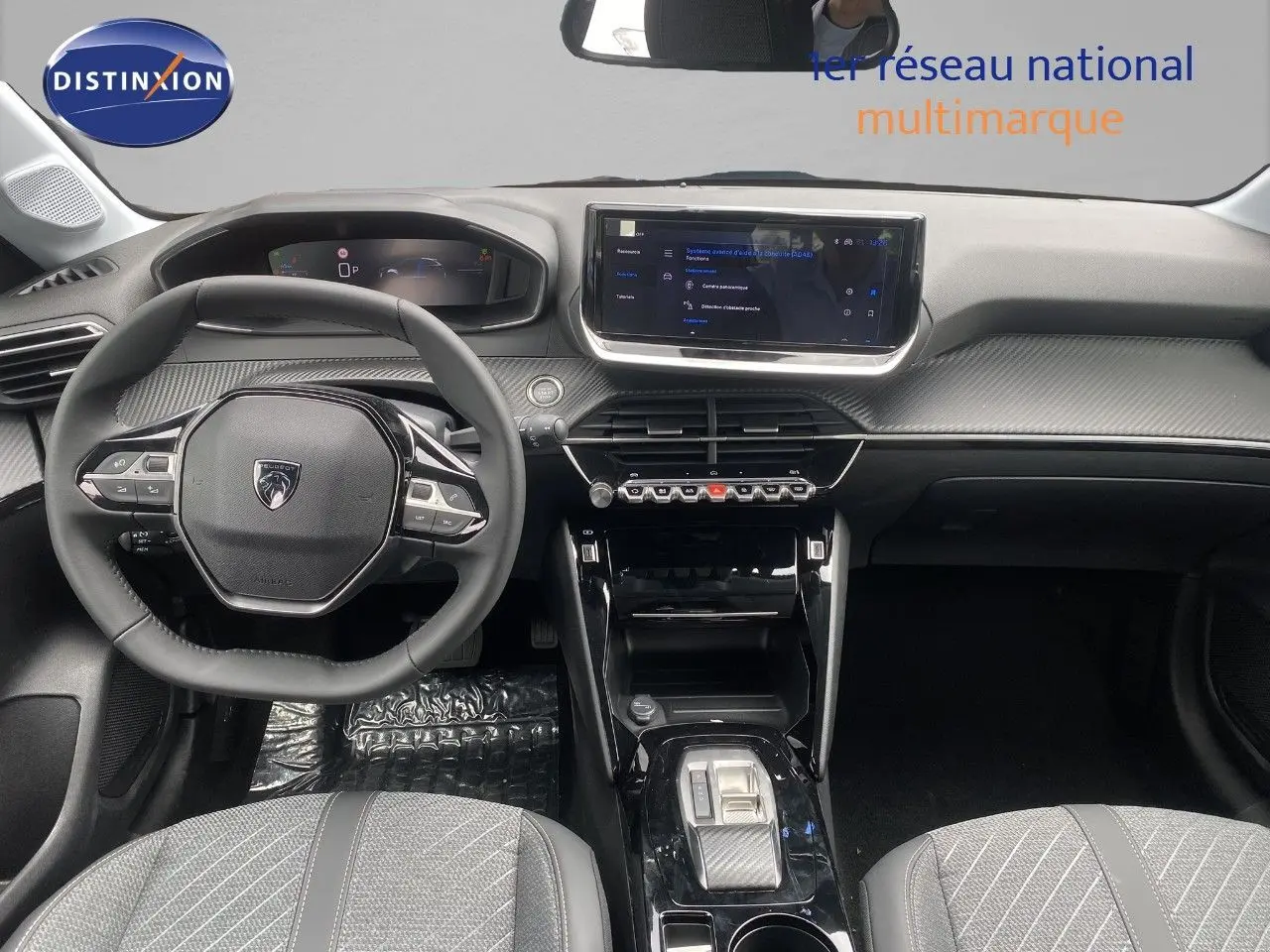 Vue intérieure avant de la Peugeot 208 Hybrid 145ch Allure 2026, tableau de bord noir avec écran tactile et volant compact.
