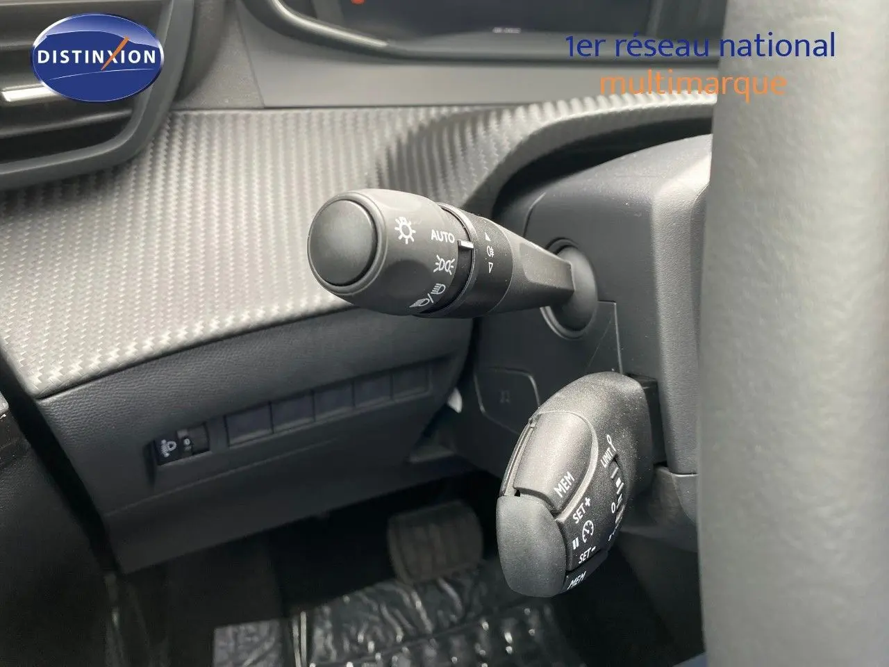 Gros plan sur les commandes au volant d’une Peugeot 208 Hybrid 145ch, avec détails des leviers de réglage et tableau de bord gris.
