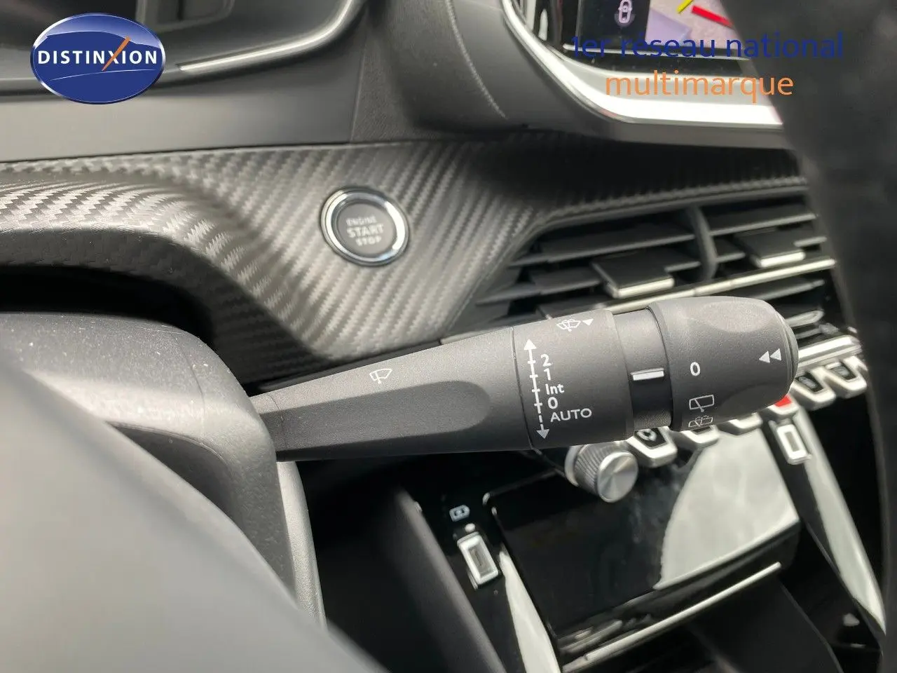 Gros plan sur la commande d’essuie-glace et le bouton start/stop, tableau de bord carbone du Peugeot 208 gris selenium.