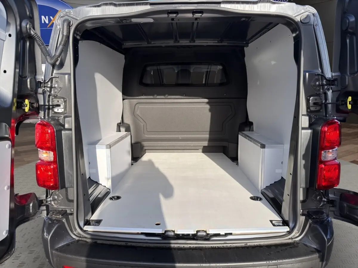 Vue arrière ouverte du Peugeot Expert Fourgon XL gris foncé, montrant l'espace de chargement vide avec cloison vitrée.