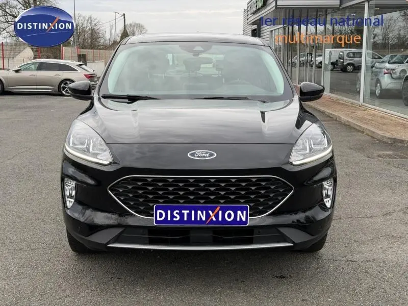 Vue frontale d'un Ford Kuga 1.5 EcoBoost 150ch Titanium noir, avec calandre hexagonale et phares LED allumés.