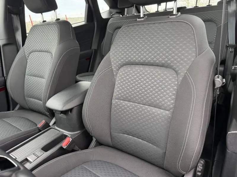 Vue intérieure rapprochée des sièges avant gris foncé du Ford Kuga 2024 Titanium avec surpiqûres et accoudoir central.