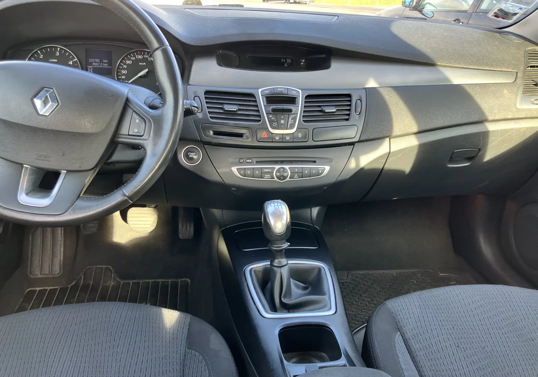 Intérieur noir de Renault Laguna 2008, vue centrale sur tableau de bord et levier de vitesses manuel en tissu.