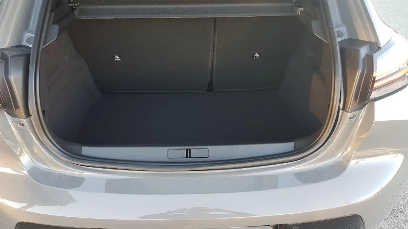 Coffre ouvert vu de l'arrière d'une Peugeot 208 Hybrid gris 2024, montrant l'espace de chargement vide.