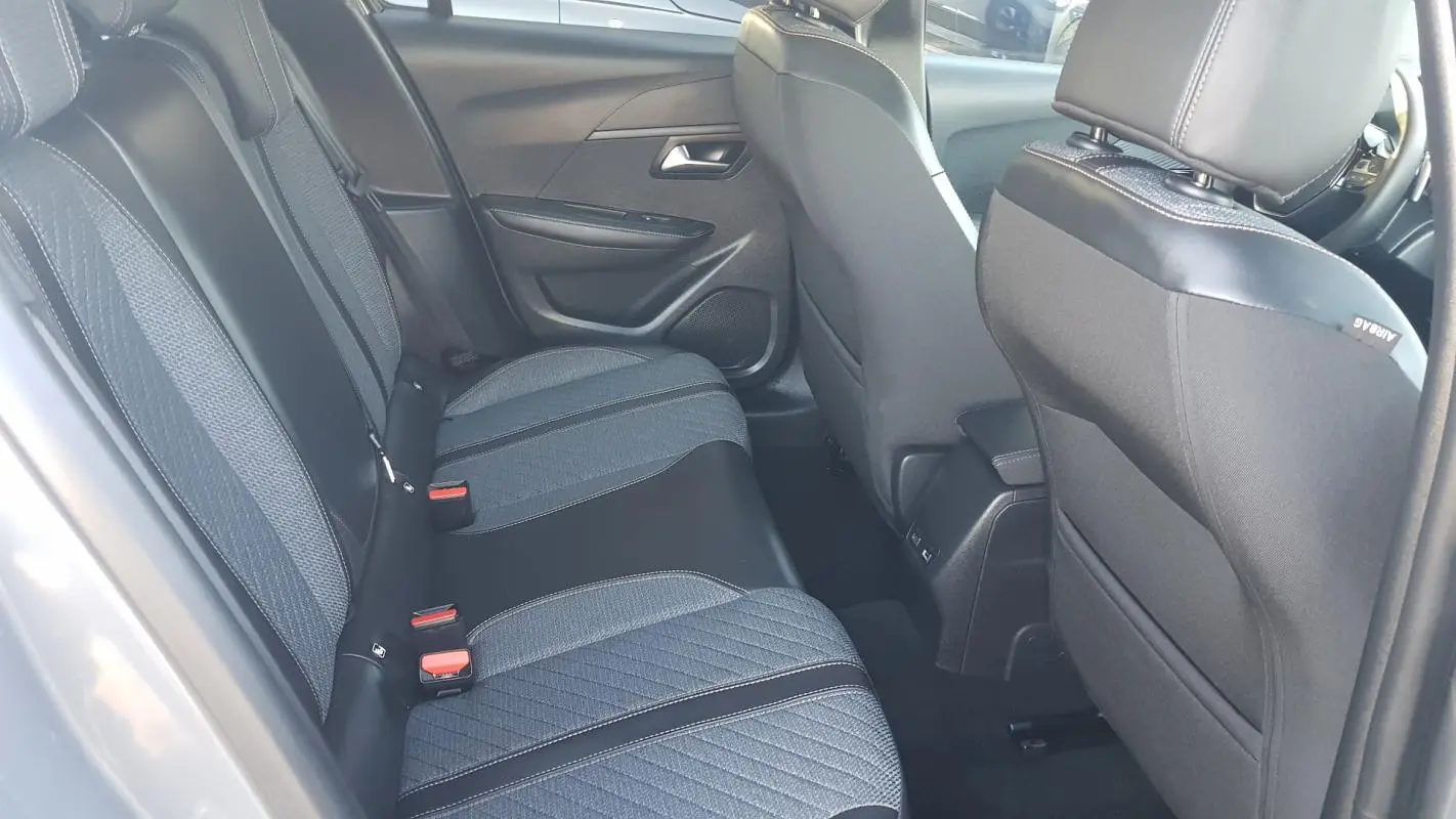 Vue intérieure des sièges arrière gris foncé et tissu texturé d'une Peugeot 208 Hybrid 2024, côté gauche.