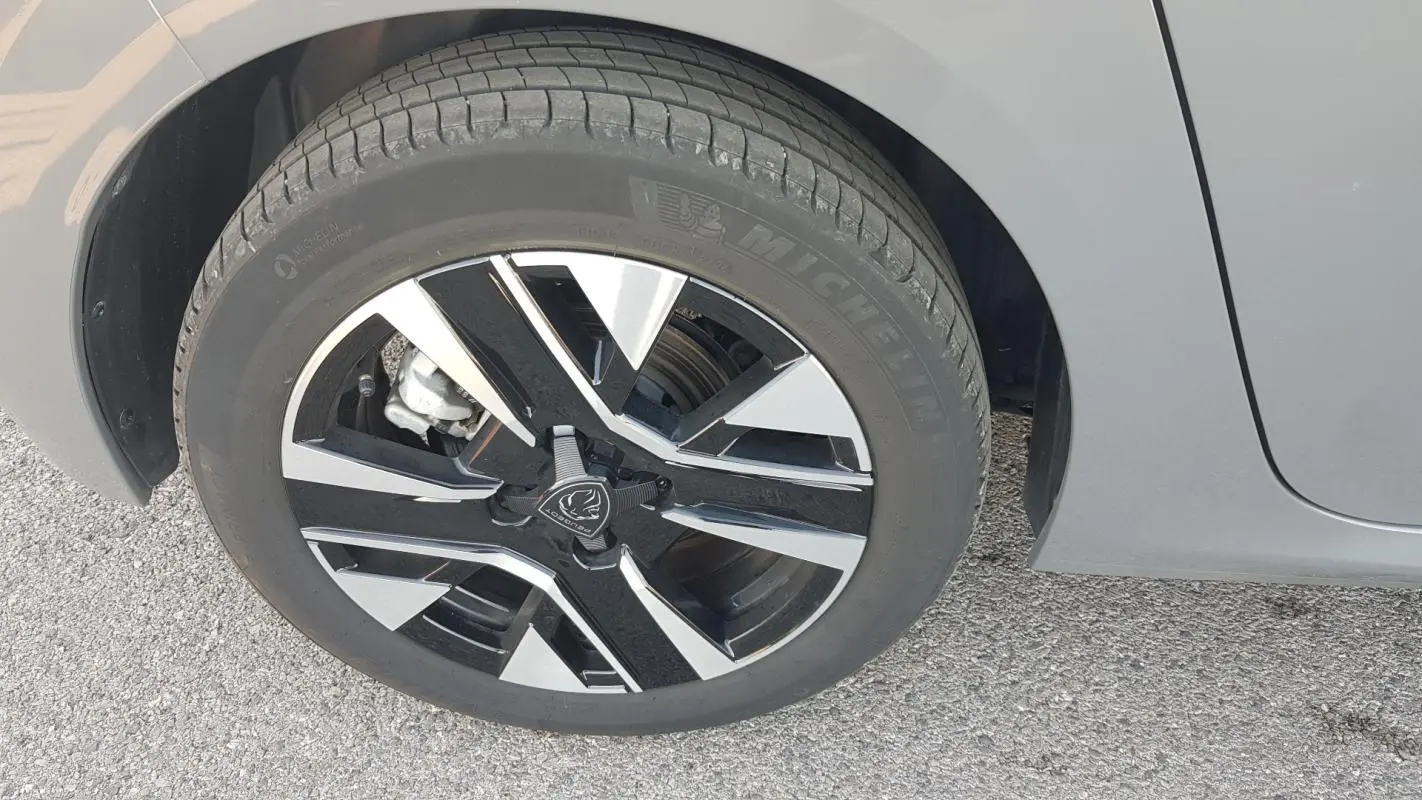 Gros plan sur la jante alliage 16 pouces noire et grise du côté gauche d'une Peugeot 208 gris 2024.