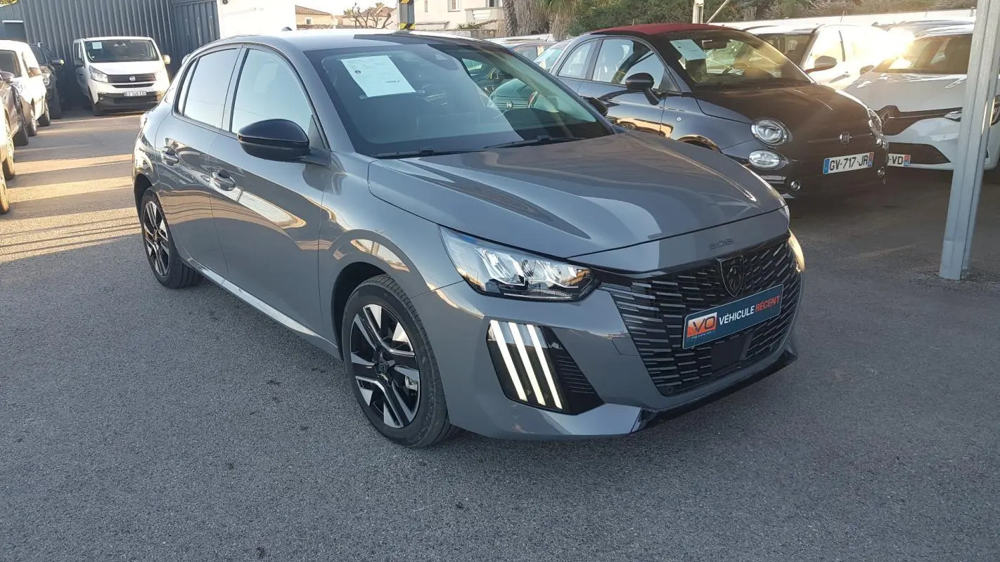 Peugeot 208 Hybrid gris vue 3/4 avant droit, avec calandre noire et feux diurnes à LED verticaux.