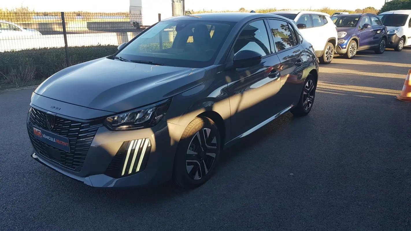 Peugeot 208 gris vue 3/4 avant droit, avec feux diurnes verticaux allumés et jantes alliage 16 pouces.