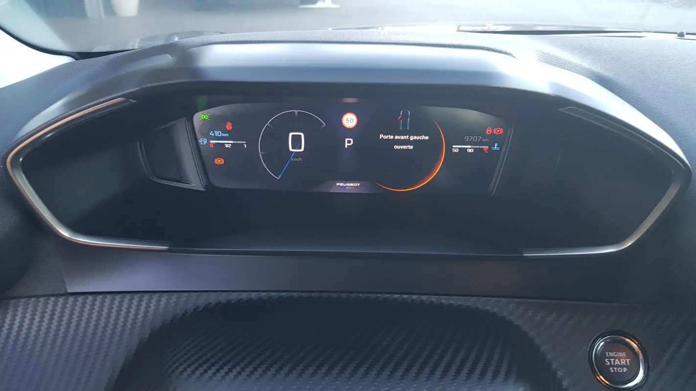 Vue rapprochée du cockpit numérique de la Peugeot 208 Hybrid 2024, affichant vitesse et alertes sur fond noir.
