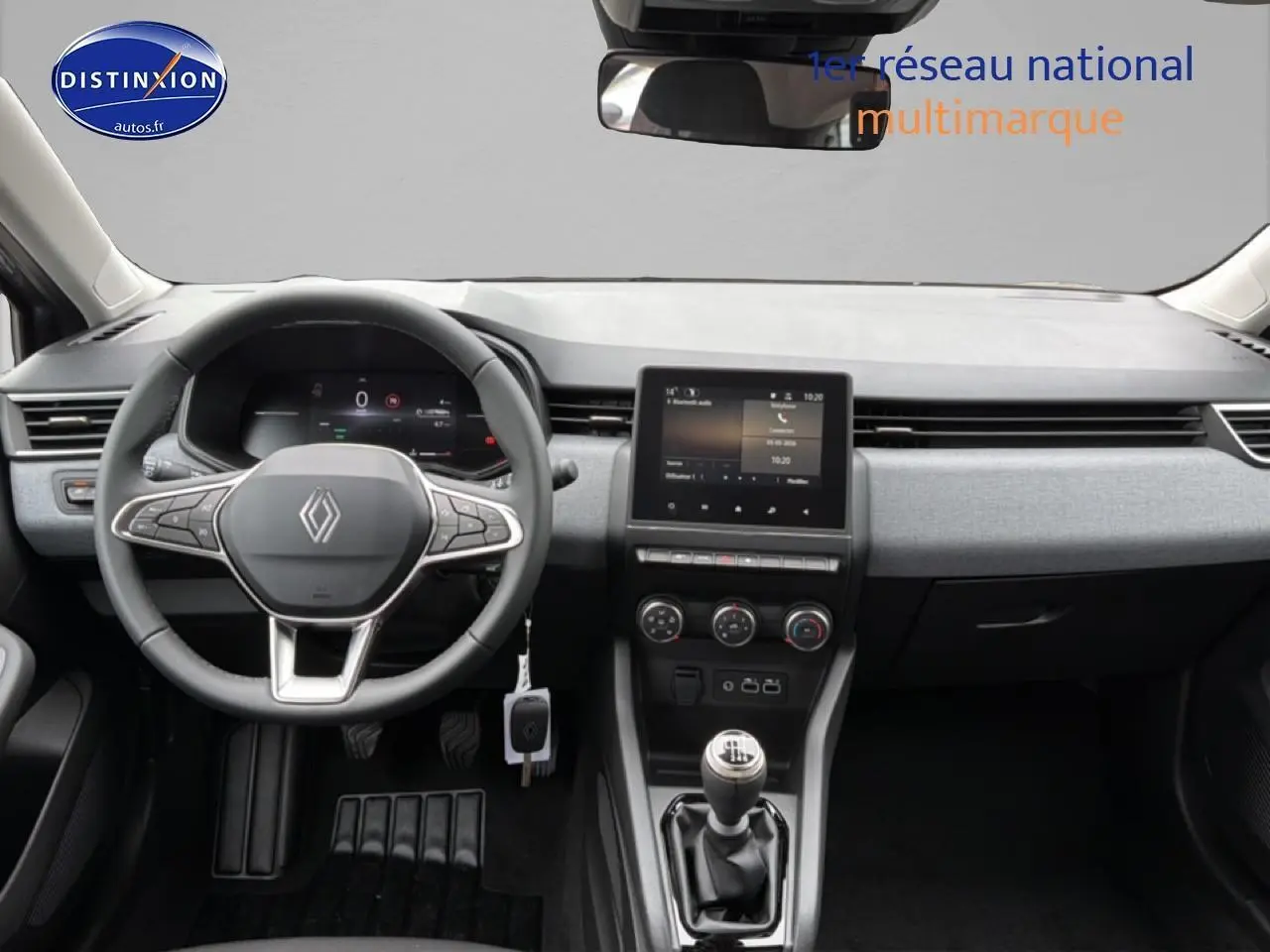 Vue intérieure frontale du tableau de bord gris clair de la Renault Clio V avec volant multifonction et écran tactile central.
