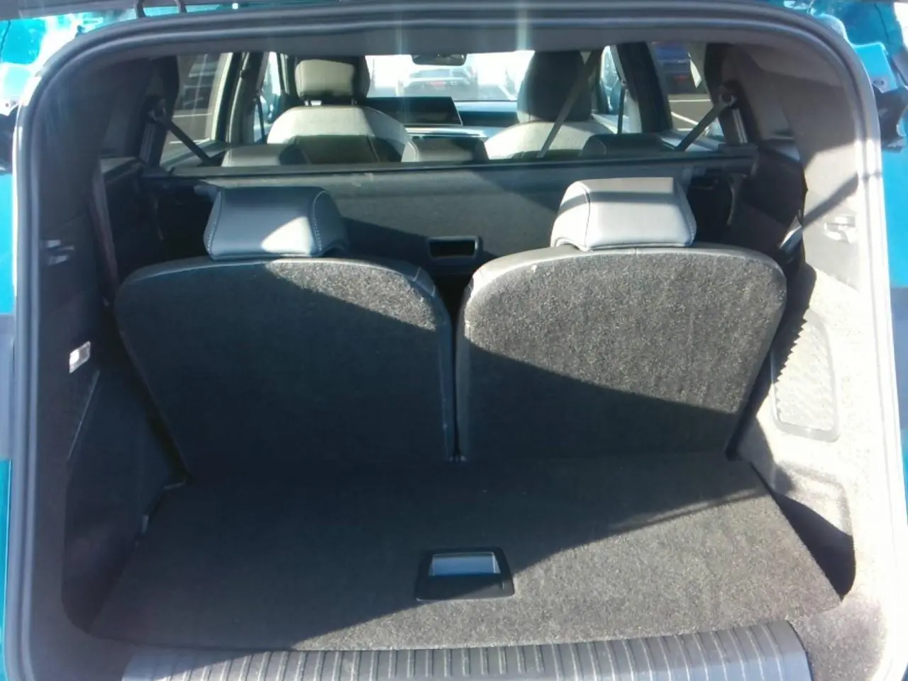Vue arrière du coffre ouvert d'un Peugeot 5008 bleu foncé, montrant la banquette arrière relevée et l'intérieur spacieux.