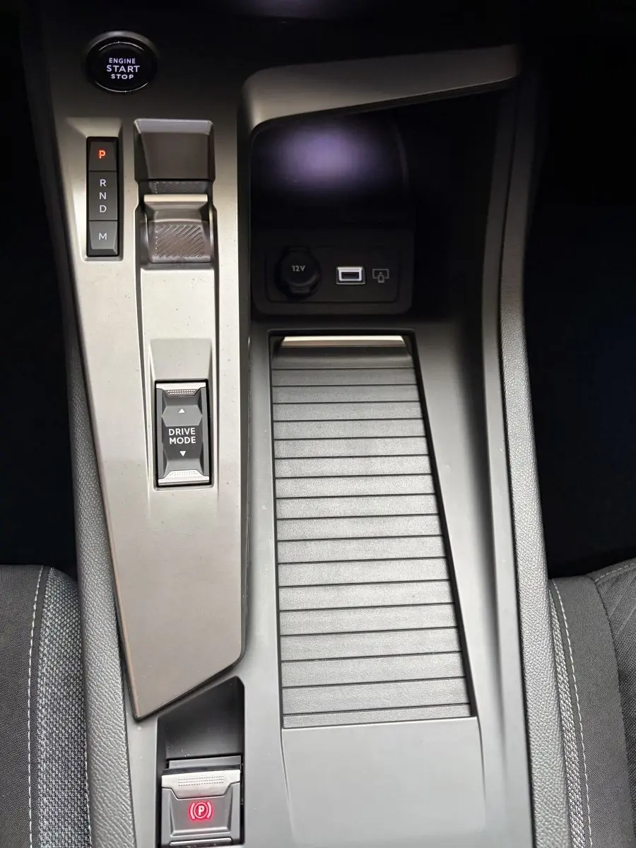 Vue rapprochée de la console centrale noire de la Peugeot 308 2024 avec bouton start, sélecteur boîte auto et prise 12V.