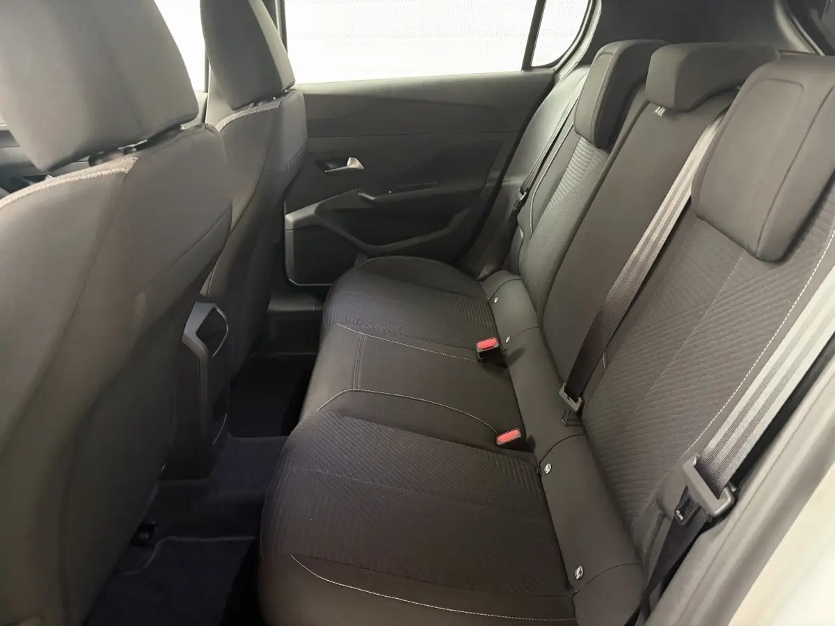 Vue intérieure côté droit des sièges arrière noirs de la Peugeot 308 2024, banquette 3 places avec ceintures visibles.