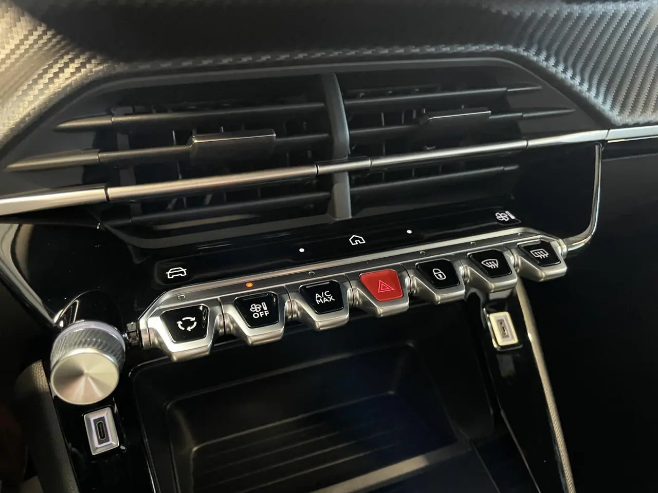 Gros plan sur la console centrale noire brillante du Peugeot 2008 2026 avec boutons de commande et ventilation.