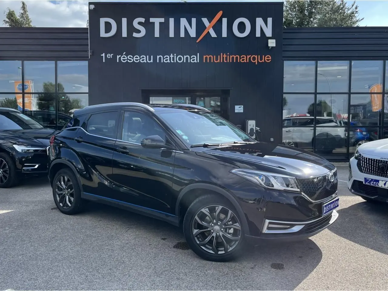 Vue 3/4 avant droite du SUV électrique SERES 3 Luxury noir métal avec jantes 18 pouces devant un concessionnaire Distinxion.