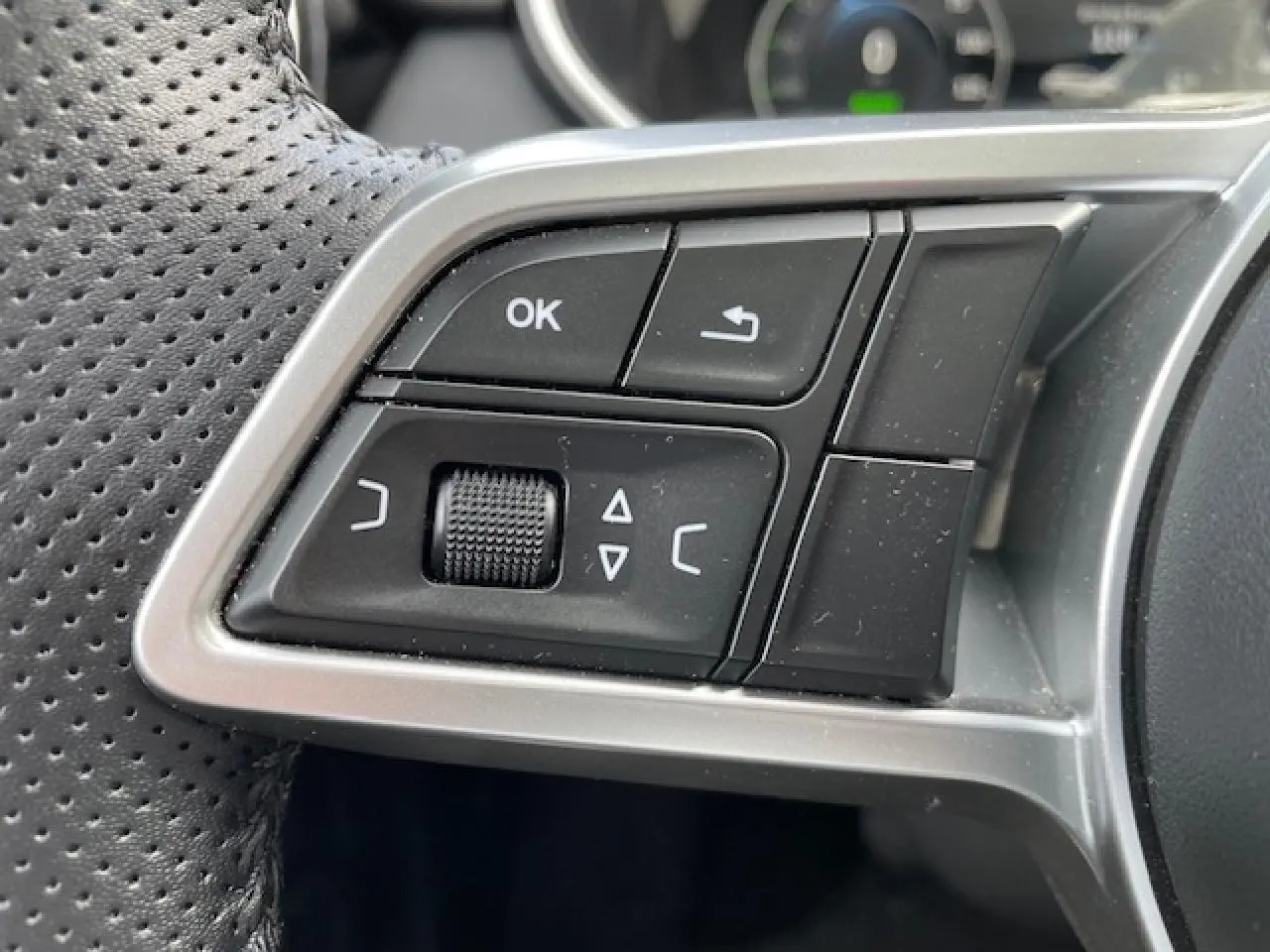 Gros plan sur les commandes multifonctions noires et argentées du volant en cuir perforé du SERES 3 Luxury 2022.