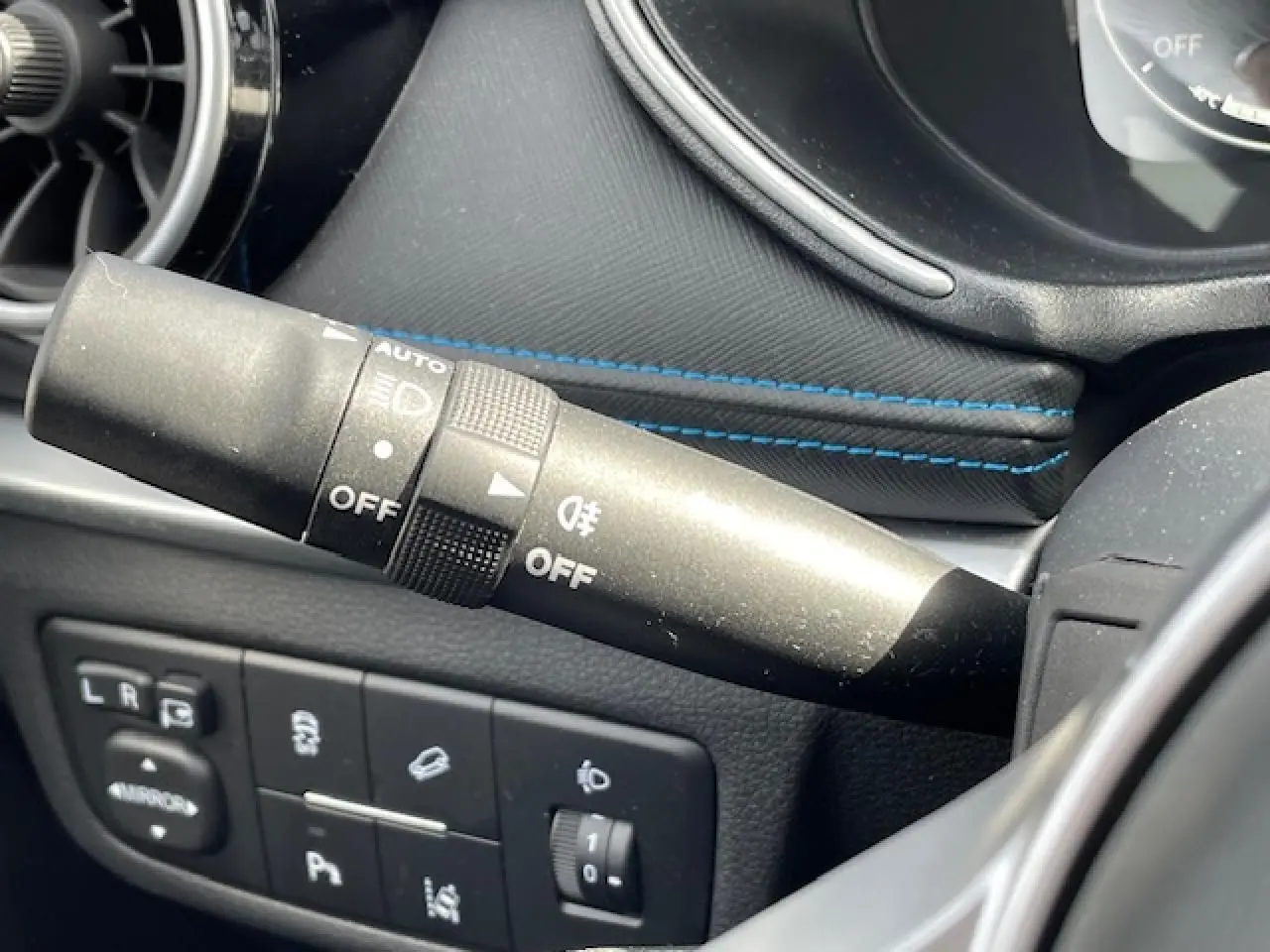 Gros plan sur la commande des phares et les boutons de réglage côté gauche du tableau de bord du SERES 3 noir métal.