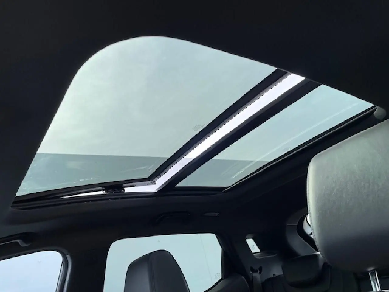 Toit panoramique ouvert vu de l'intérieur arrière d'un SERES 3 Luxury noir métal avec sièges en similicuir.