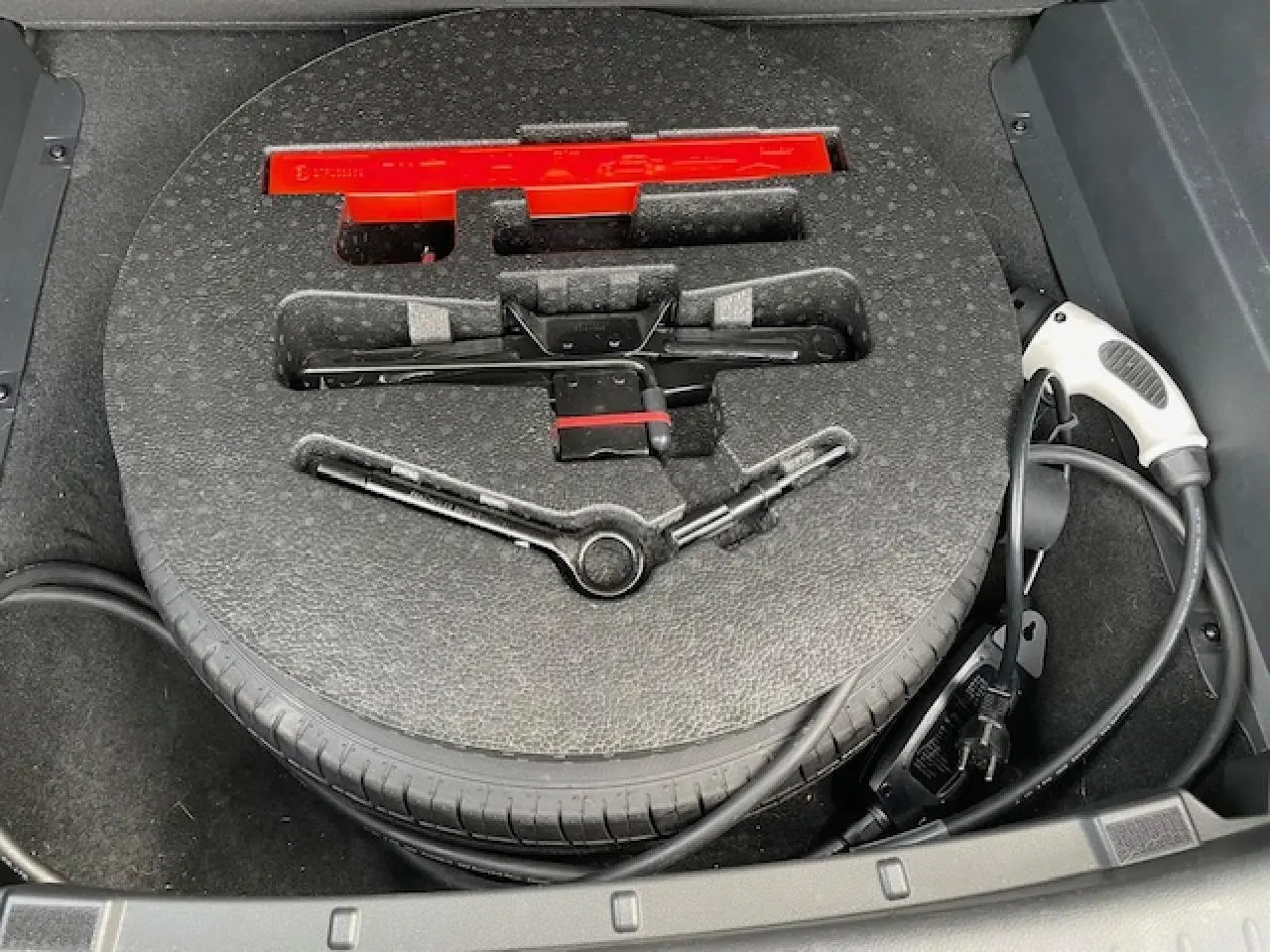 Gros plan sur la roue de secours et le chargeur électrique dans le coffre du SERES 3 Luxury noir métal 2022.