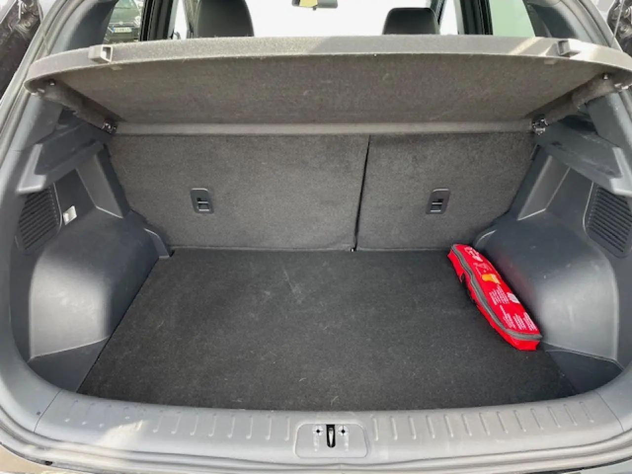 Coffre ouvert vu de l'arrière du SERES 3 noir métal, avec un kit de secours rouge posé à droite.