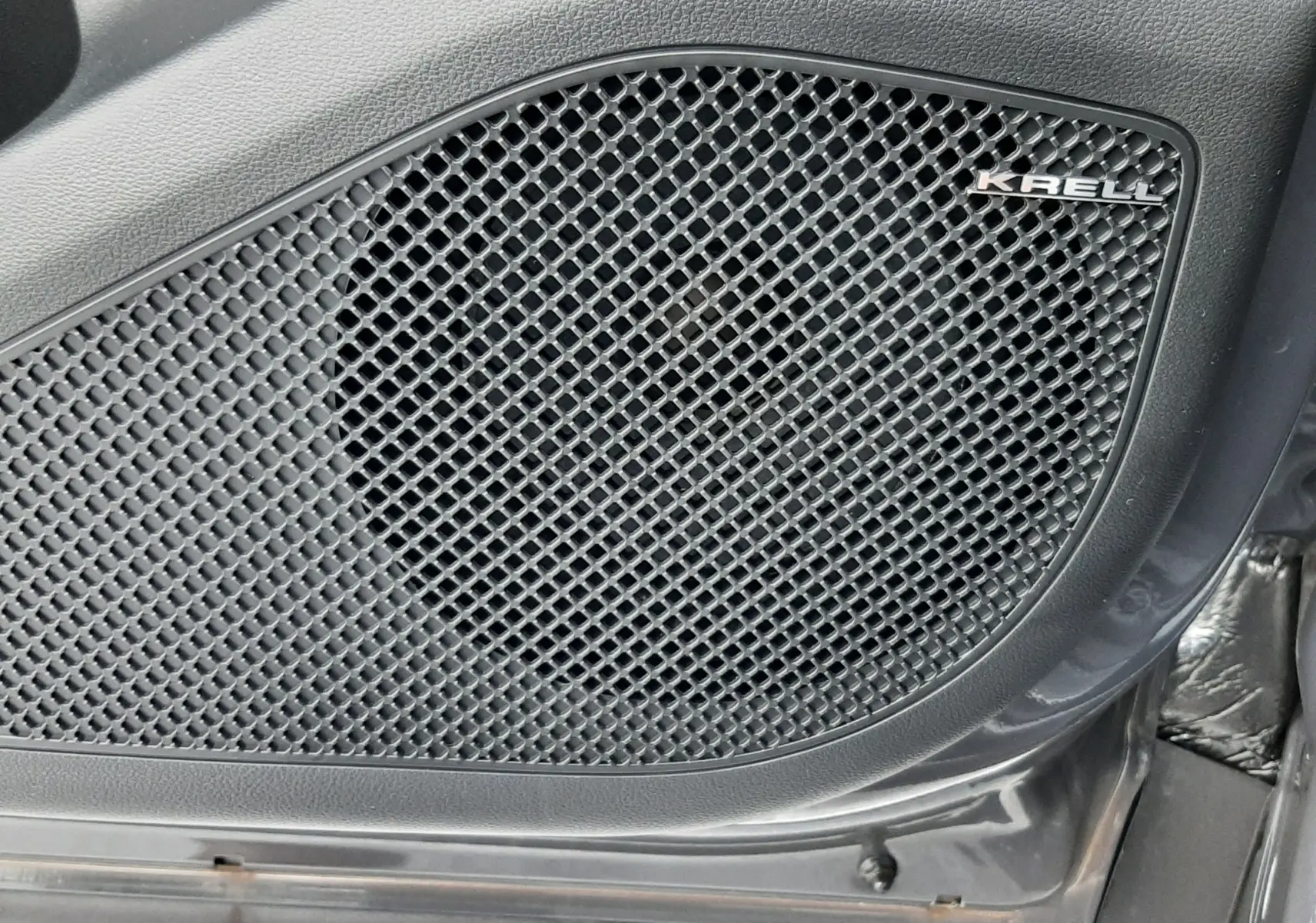 Gros plan sur le haut-parleur Krell intégré à la porte intérieure noire du Hyundai Tucson 2025 Ecotronic Grey hybride