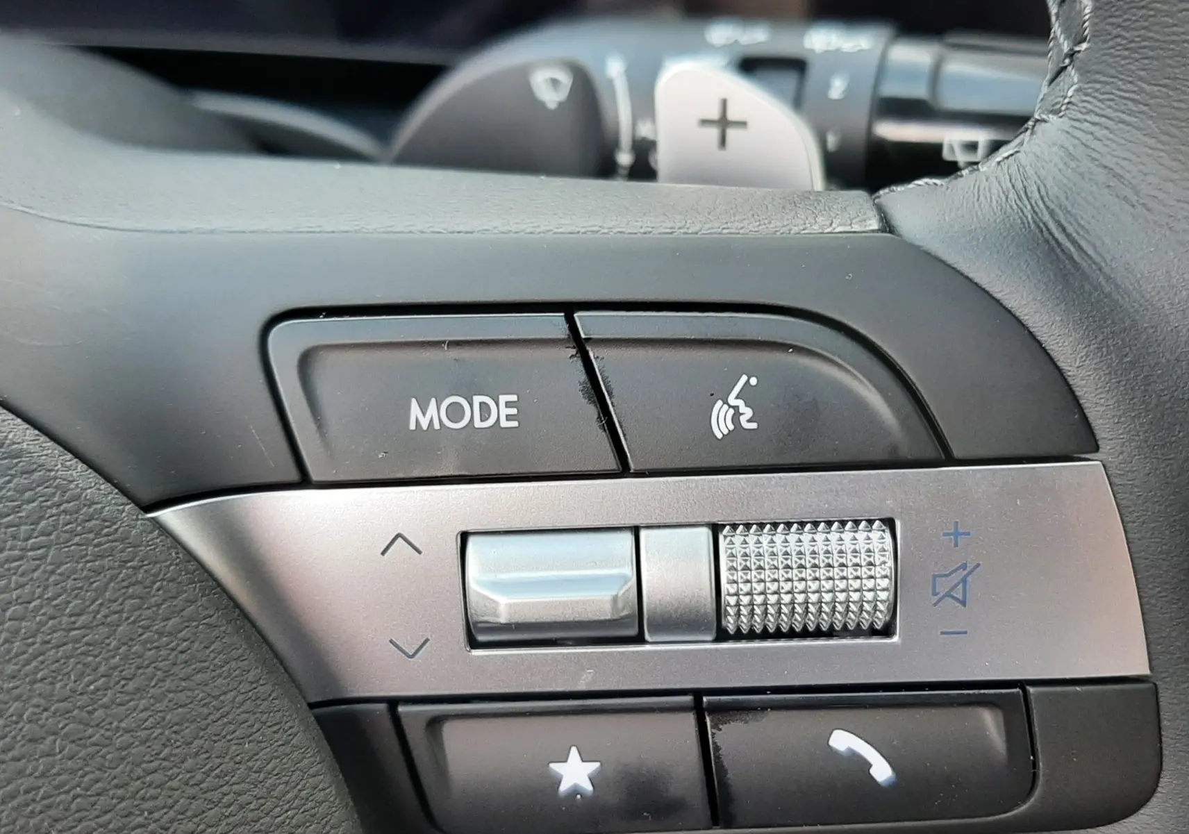 Gros plan sur les commandes du volant cuir noir du Hyundai Tucson 2025, avec molette de volume et bouton mode.