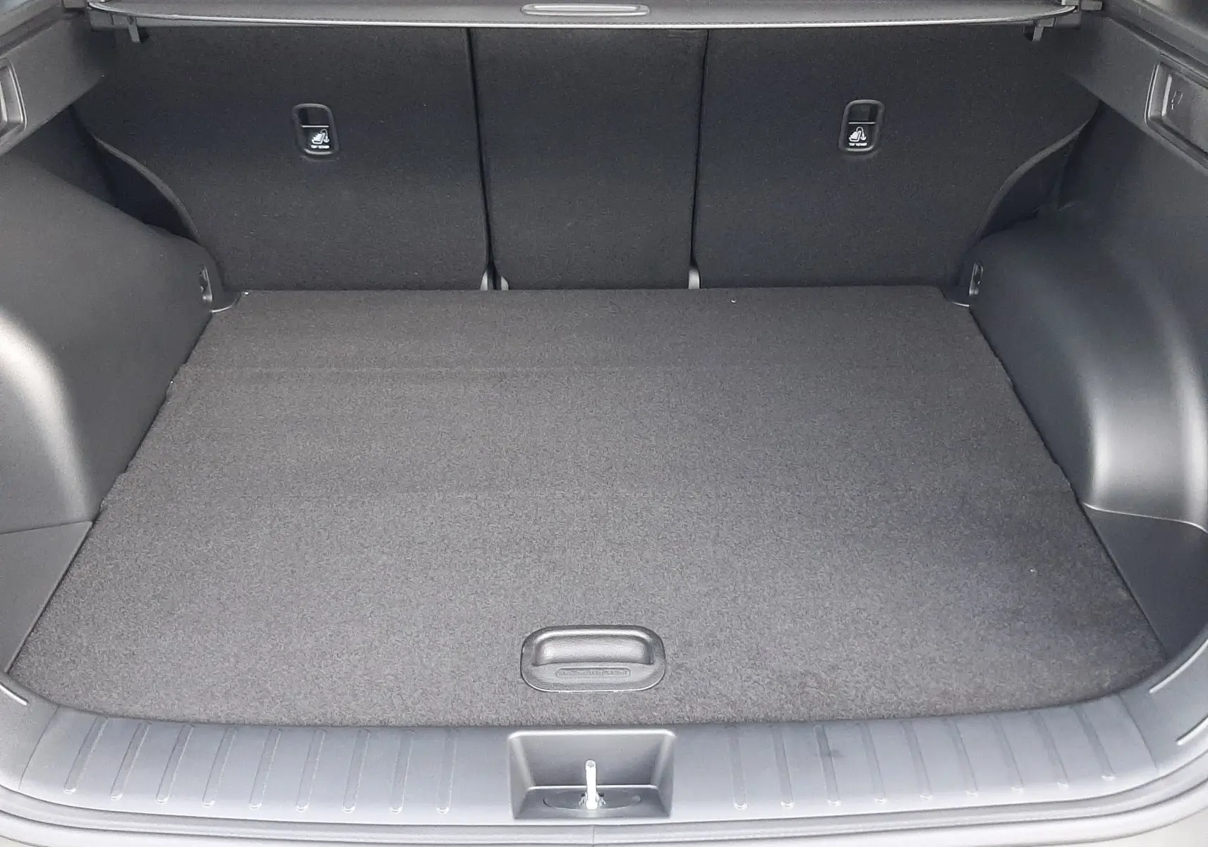 Coffre ouvert vu de l'arrière d'un Hyundai Tucson 2025 gris Ecotronic, avec cache-bagages et sièges noirs.
