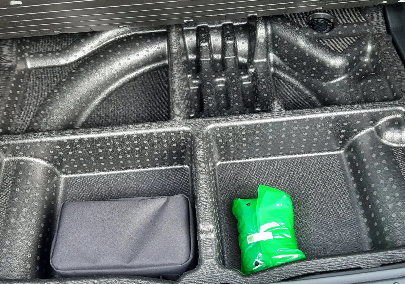 Compartiment de rangement noir sous le plancher du coffre du Hyundai Tucson 2025 en Ecotronic Grey.