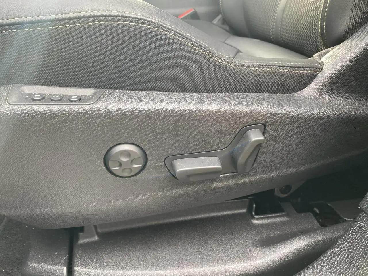 Gros plan sur les commandes de réglage électrique du siège conducteur noir du Peugeot 3008 Hybrid 2023.