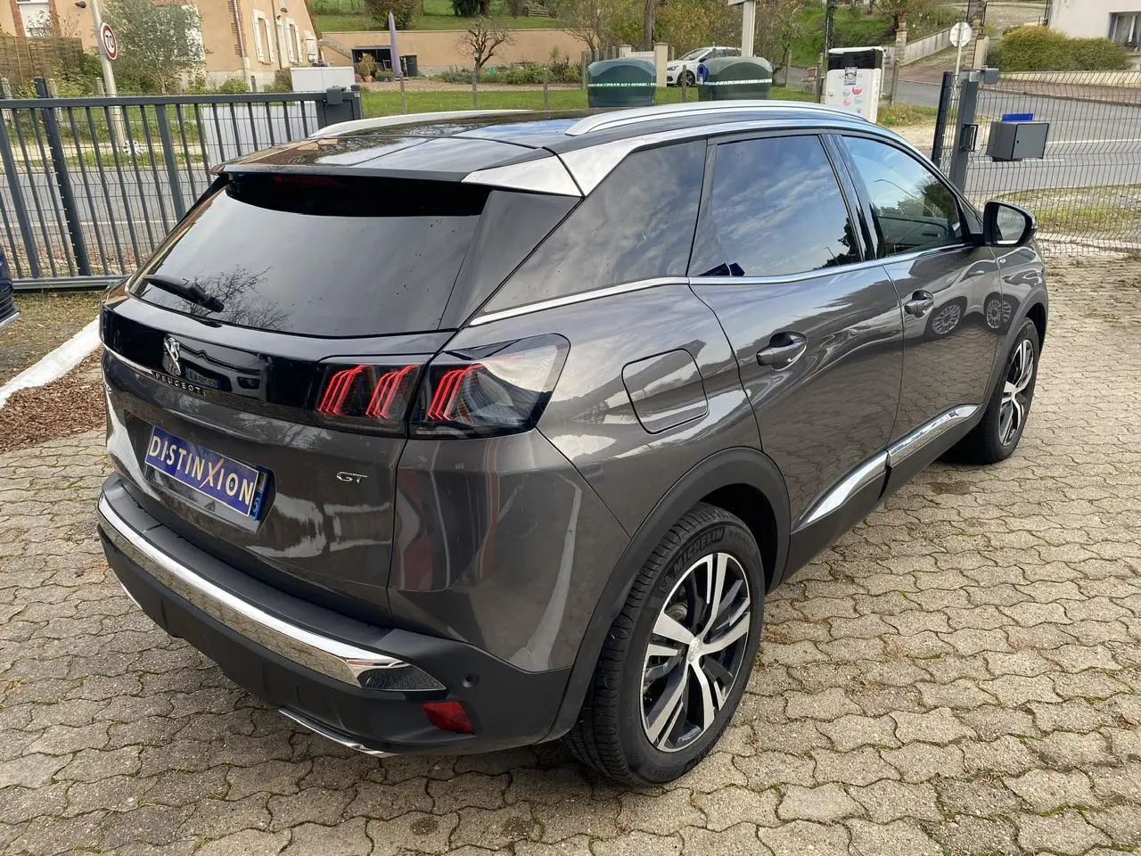 Peugeot 3008 gris foncé en 3/4 arrière droit, avec feux arrière LED et coques de rétroviseurs noires.