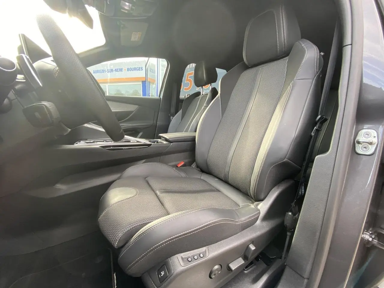 Vue intérieure côté conducteur du siège avant en cuir noir avec surpiqûres blanches du Peugeot 3008 gris foncé 2023.