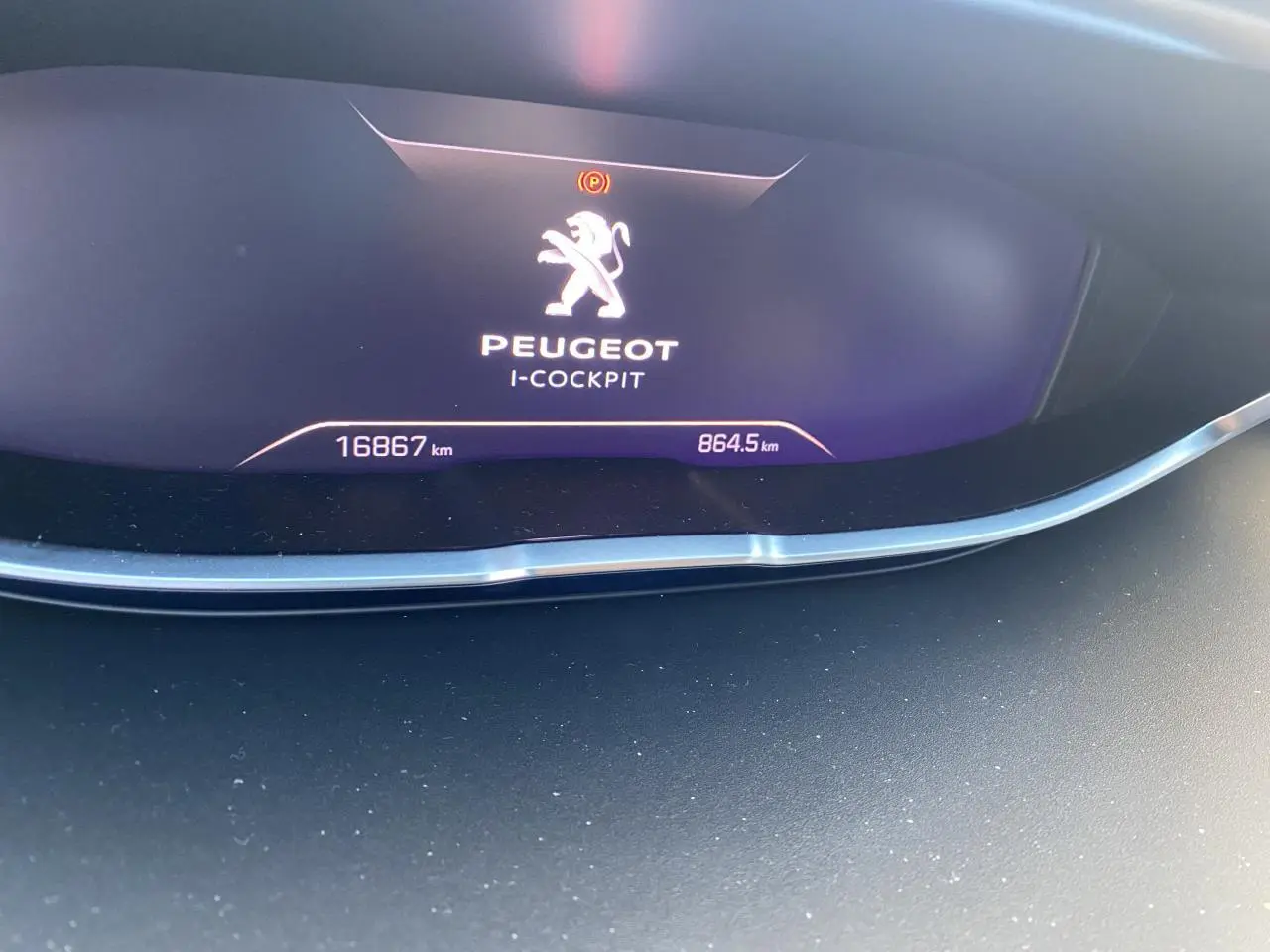 Affichage numérique du tableau de bord Peugeot i-Cockpit du 3008 hybride, montrant le logo et le kilométrage.
