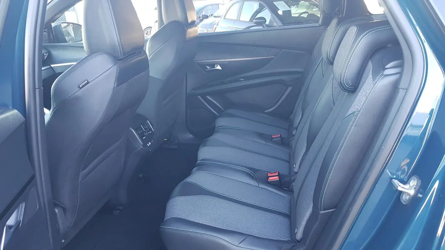 Vue intérieure côté droit sur la banquette arrière tissu et cuir du Peugeot 5008 bleu avec appuie-têtes et ceintures rouges.