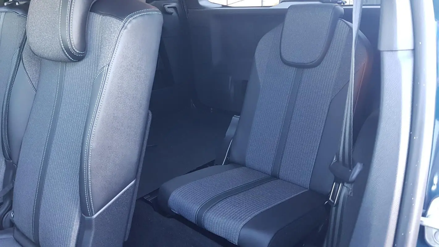 Vue intérieure sur les sièges arrière en tissu gris et noir du Peugeot 5008 bleu, avec ceinture de sécurité visible.