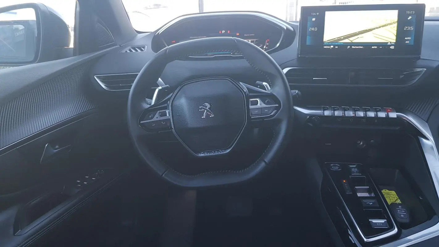 Vue intérieure centrée sur le volant cuir et le cockpit numérique du Peugeot 5008 2024, avec écran tactile et commandes modernes.