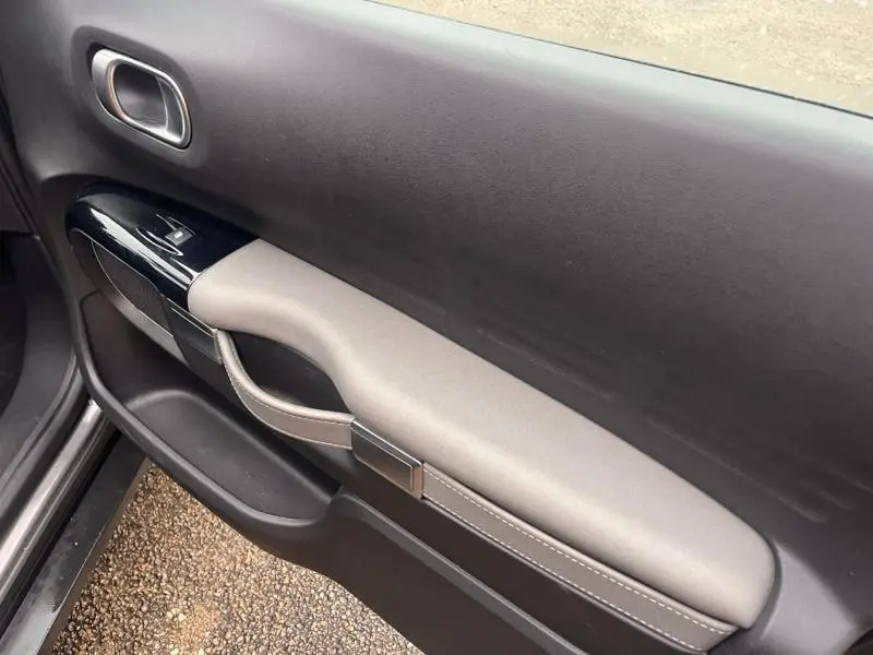Vue intérieure côté gauche de la porte avant d'une Citroën C4 Cactus 2020 gris Platinium avec accoudoir gris et finitions noires brillantes.
