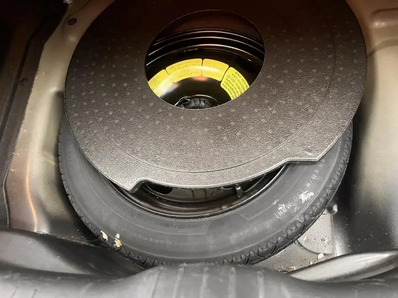 Gros plan sur la roue de secours et son support en mousse dans le coffre d'une Citroën C4 Cactus Gris Platinium.