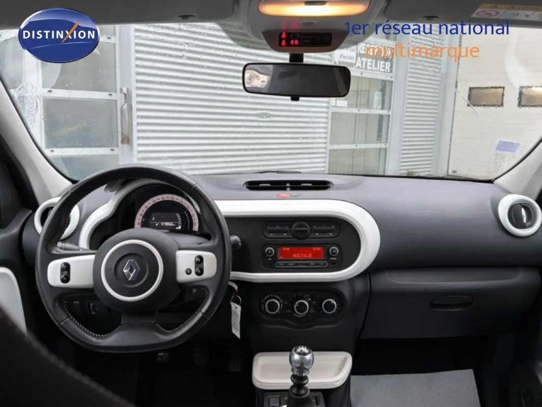 Vue intérieure avant de la Renault Twingo III gris foncé, volant cuir, tableau de bord avec commandes et boîte manuelle.