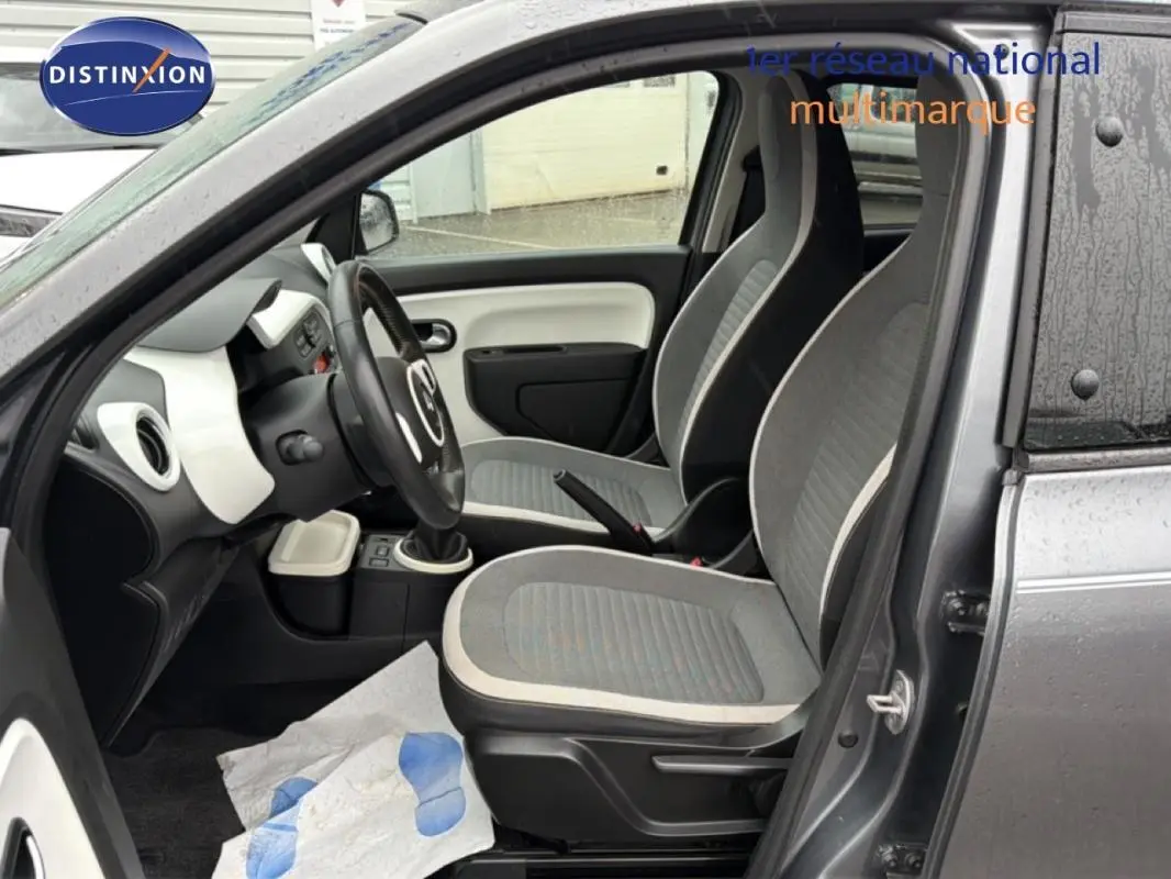 Vue intérieure côté conducteur de la Renault Twingo III gris foncé, montrant les sièges et le volant cuir.