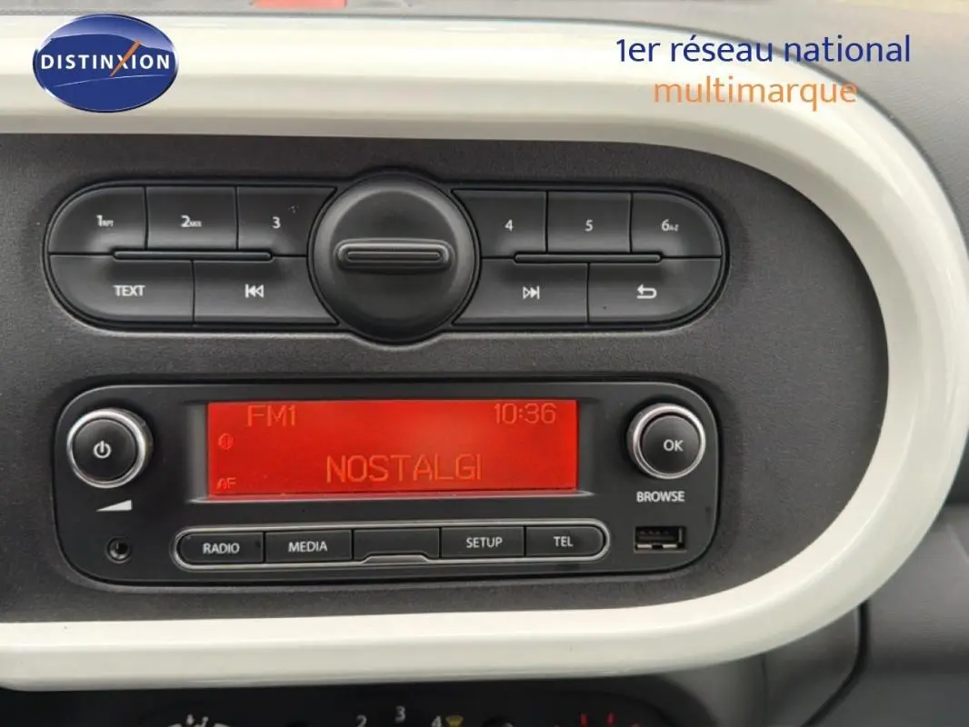 Tableau de bord de Renault Twingo III gris foncé, affichage radio rouge et commandes audio visibles en gros plan.