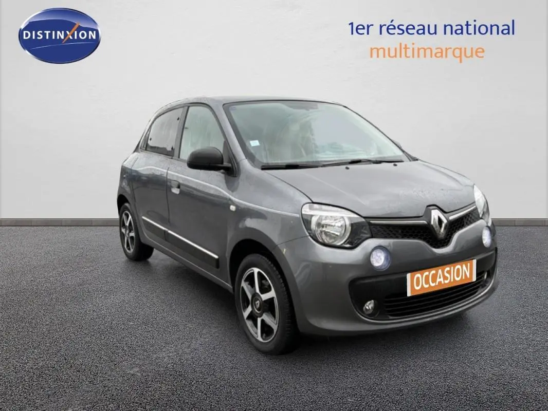 Renault Twingo III gris foncé vue 3/4 avant droit, avec jantes alliage et phares antibrouillard allumés.