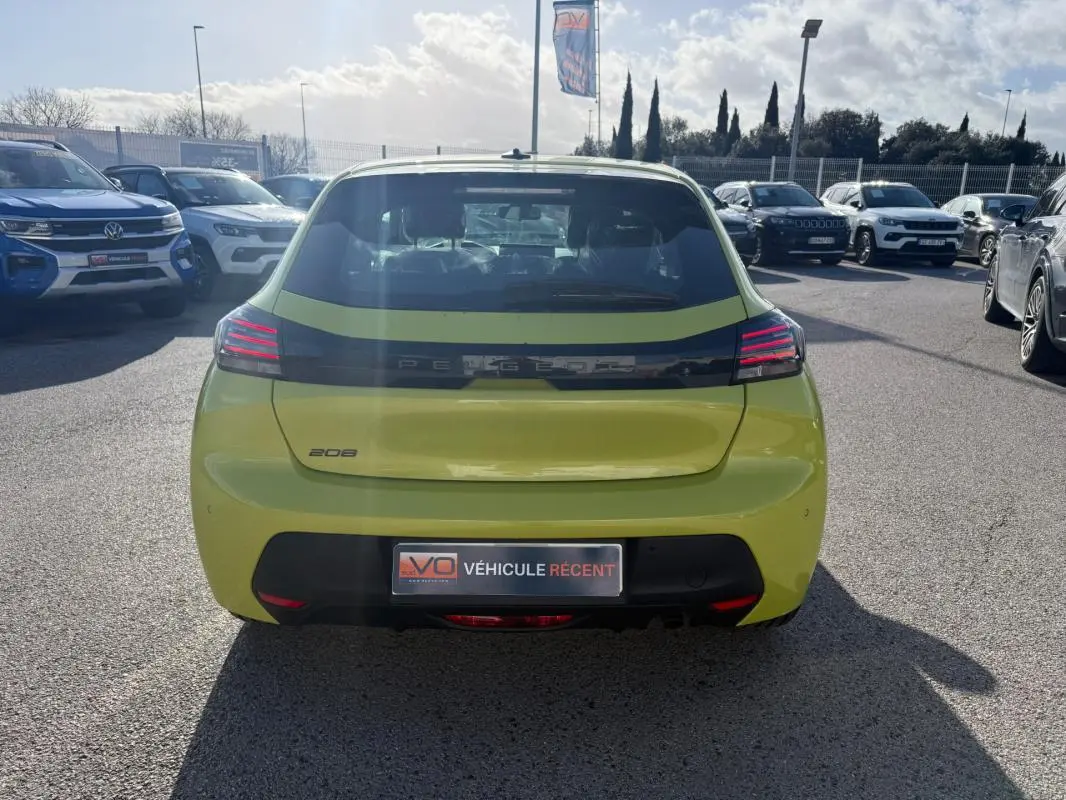Vue arrière d'une Peugeot 208 jaune 2025 garée en extérieur, avec feux arrière LED et logo distinctif visible.