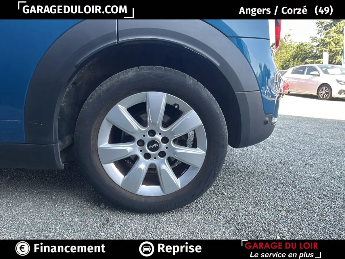 Gros plan sur la roue arrière droite argentée du MINI Countryman Cooper bleu, avec partie basse de la carrosserie visible.