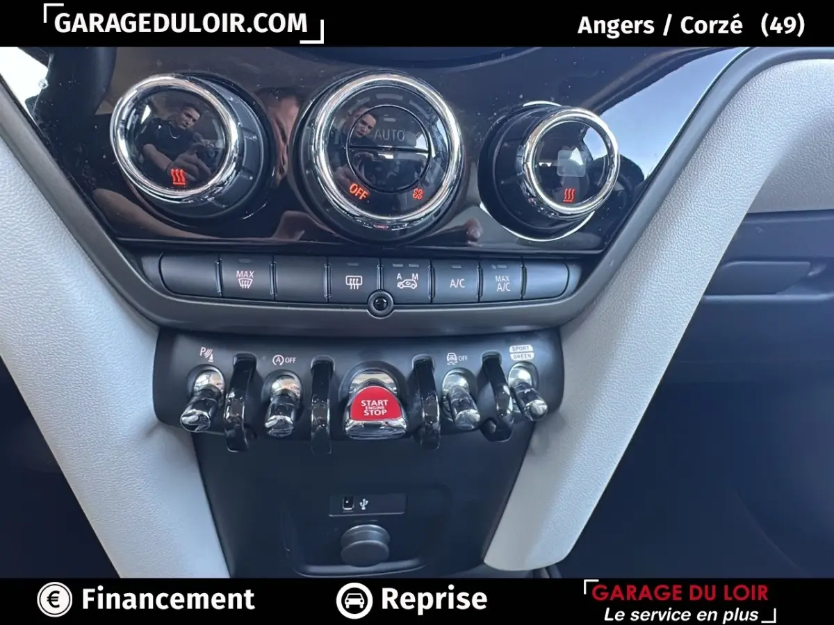 Gros plan sur la console centrale noire et grise du MINI Countryman bleu, avec boutons chrome et bouton start/stop rouge.