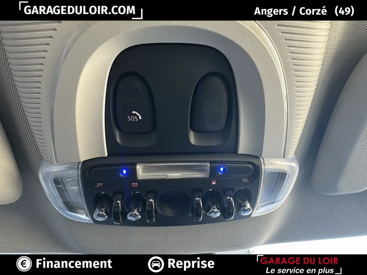 Vue en plongée sur la console de plafonnier intérieure grise avec interrupteurs chromés et voyants bleus allumés d'une MINI Countryman bleue.