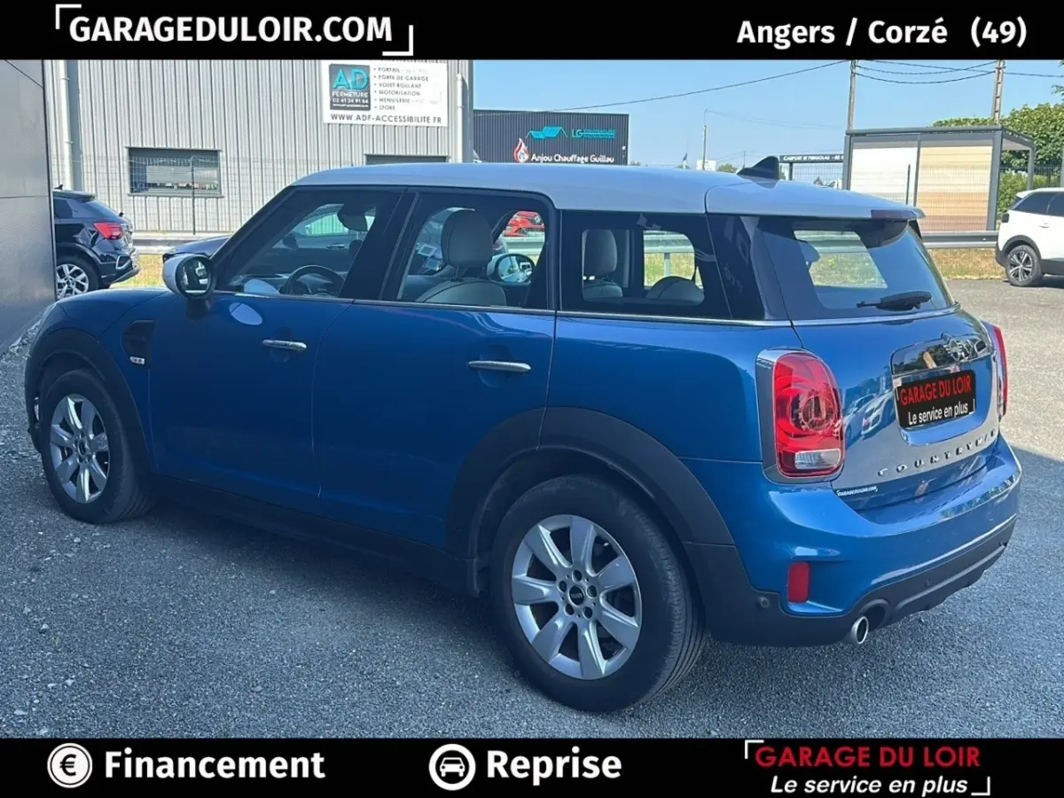 Vue 3/4 arrière droite d'une MINI Countryman Cooper bleu avec toit blanc et feux arrière LED, stationnée en extérieur.