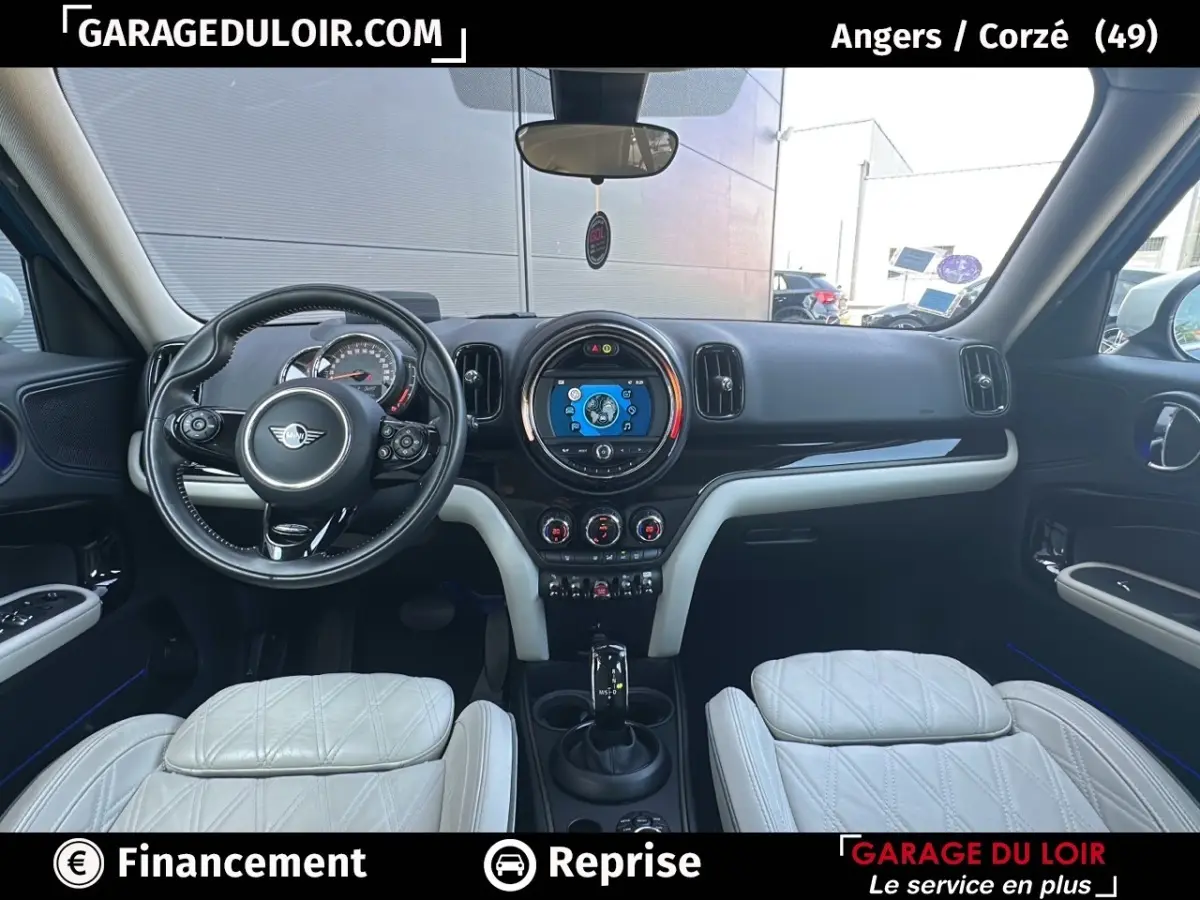 Vue intérieure avant du tableau de bord et volant cuir noir du MINI Countryman Cooper bleu avec sièges blancs.