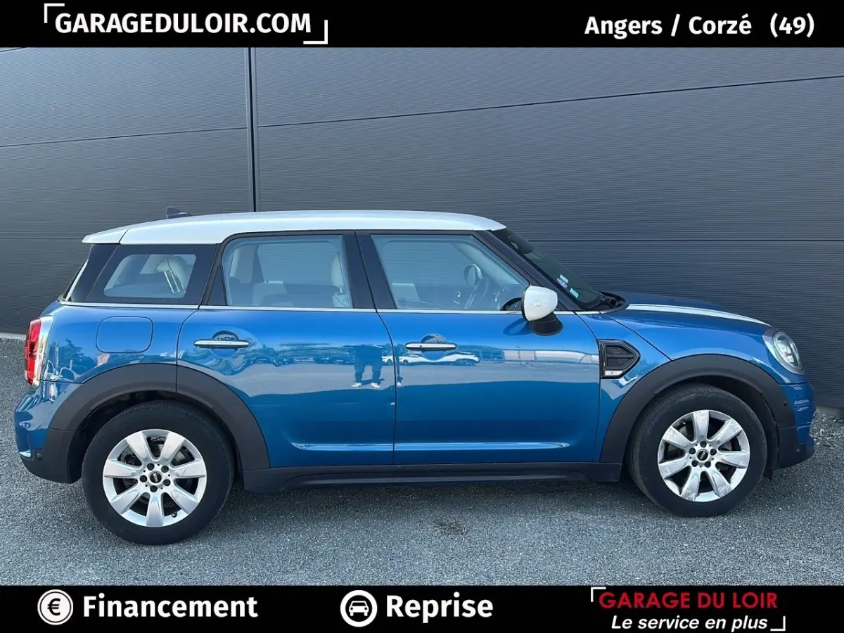 Vue de profil côté gauche d'une MINI Countryman Cooper bleu avec toit blanc et jantes argentées sur fond gris.