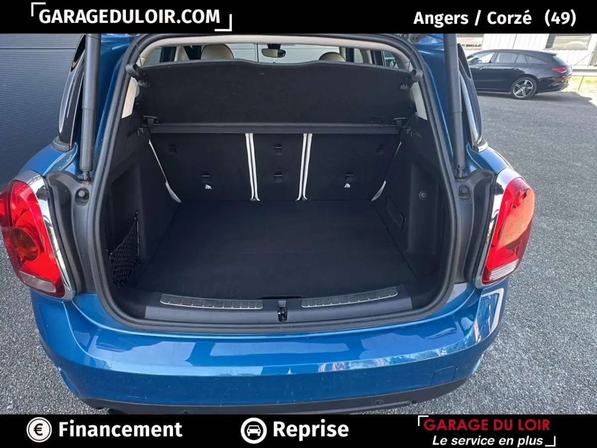 Coffre ouvert d'une MINI Countryman Cooper bleu, vue arrière mettant en valeur l'espace de chargement et les feux arrière rouges.